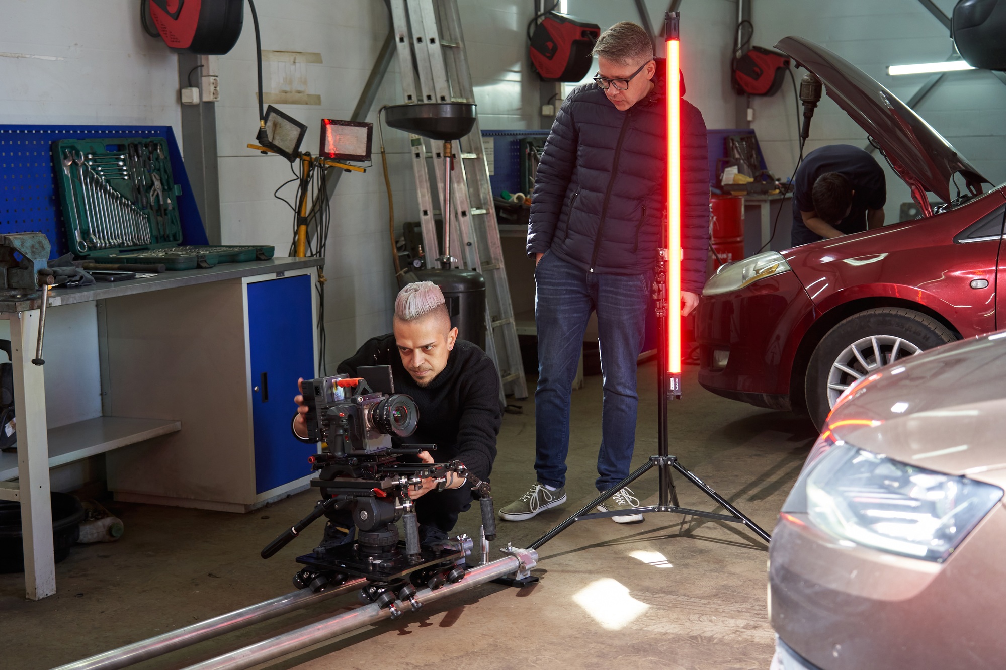 A director watches as a cameraman sets up a professional movie camera before filming on the set. the